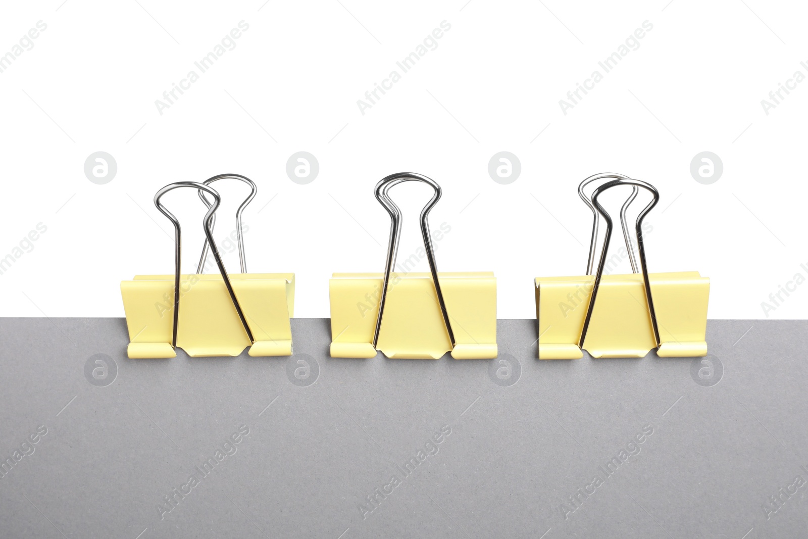 Photo of Grey paper with yellow binder clips isolated on white