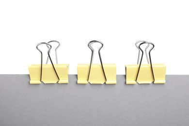 Grey paper with yellow binder clips isolated on white