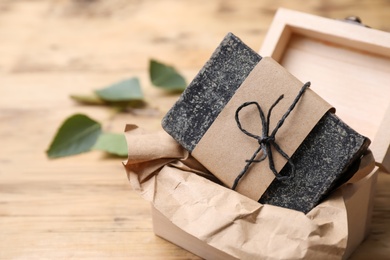 Natural tar soap in box on wooden table, closeup. Space for text