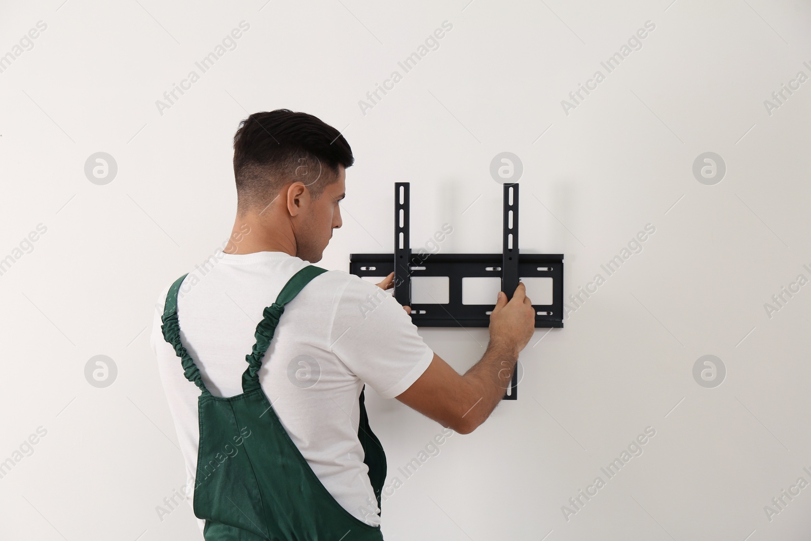 Photo of Professional technician installing TV bracket on wall indoors