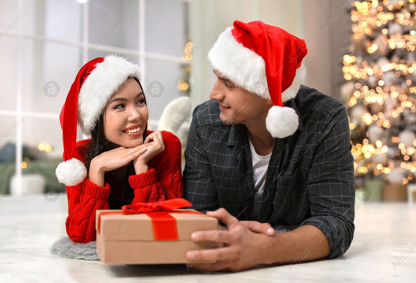 Photo of Man presenting Christmas gift to his girlfriend at home