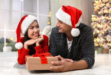 Man presenting Christmas gift to his girlfriend at home