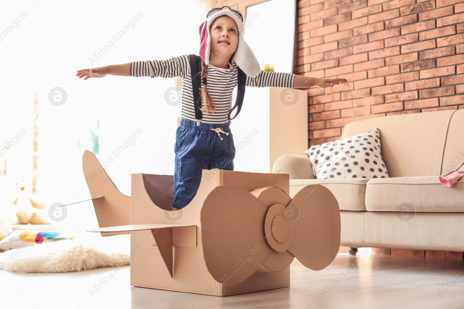 Photo of Adorable little child playing with cardboard plane at home