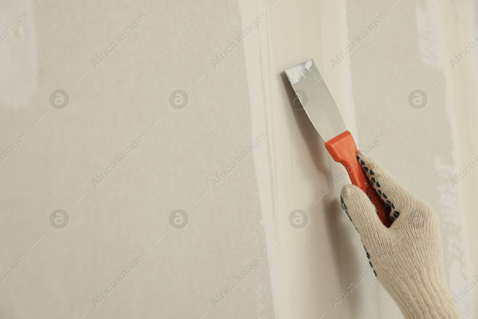 Photo of Worker plastering wall with putty knife, closeup. Space for text