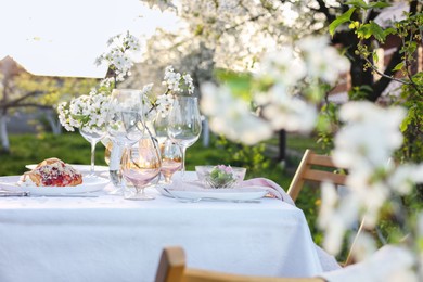 Stylish table setting with beautiful spring flowers in garden