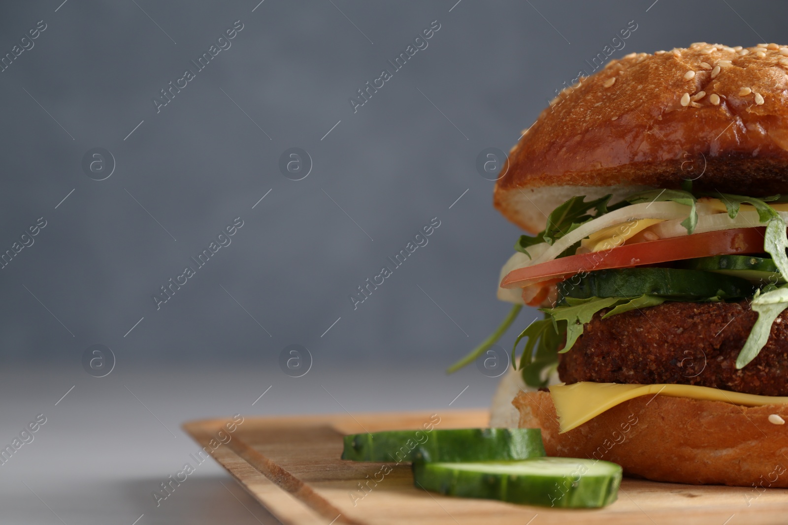 Photo of Board with delicious vegetarian burger on white table, closeup. Space for text