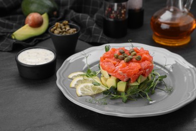 Delicious salmon tartare served with avocado and lemon on dark table