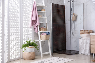 Photo of Bathroom interior with shower stall and shelving unit. Idea for design