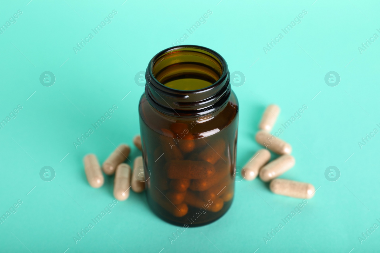 Photo of Gelatin capsules and bottle on turquoise background, closeup