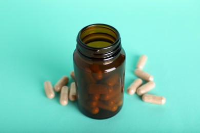 Photo of Gelatin capsules and bottle on turquoise background, closeup