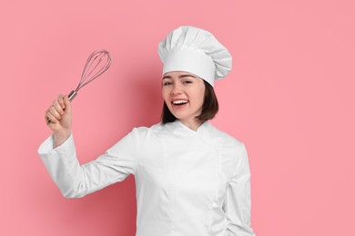 Photo of Happy confectioner with whisk on pink background