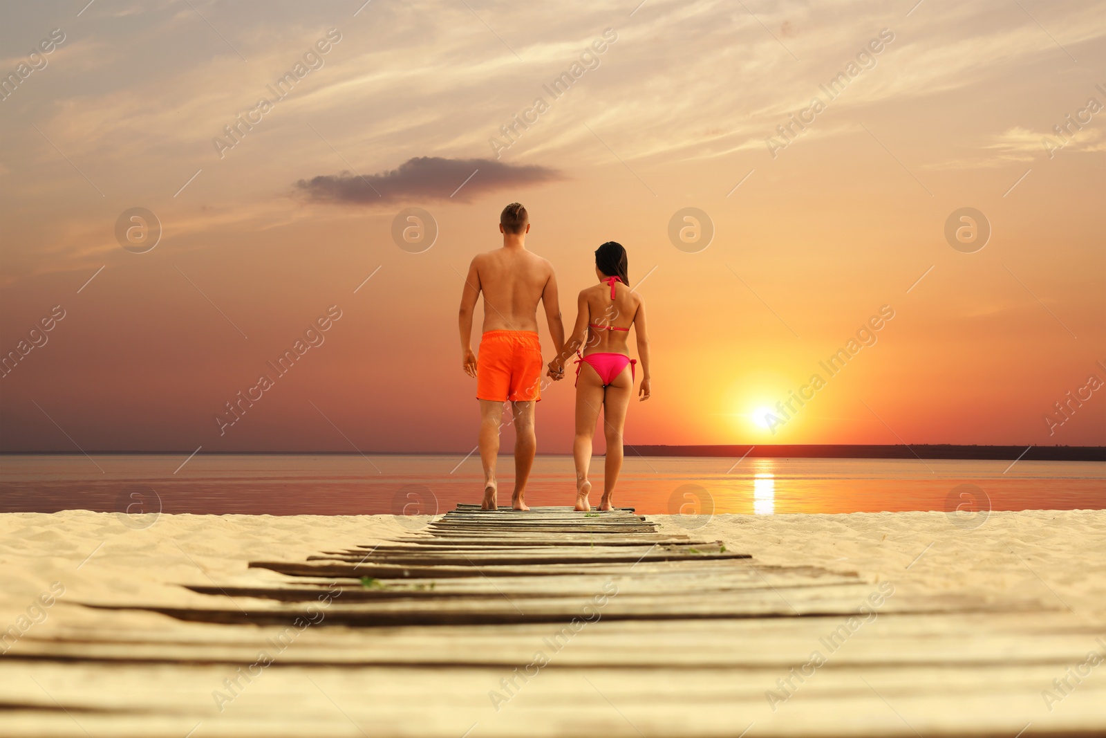 Photo of Young woman in bikini spending time with her boyfriend on beach. Lovely couple