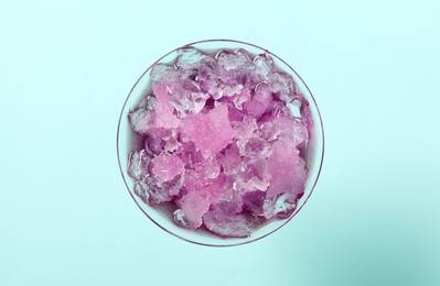 Shaving ice in martini glass on light blue background, top view