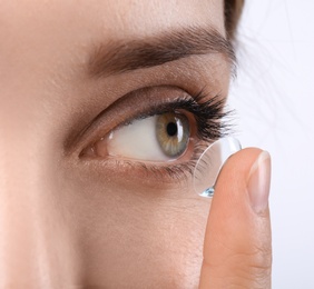 Young woman putting contact lens in her eye, closeup