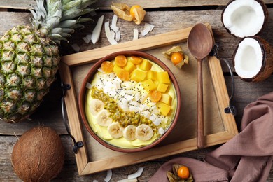 Photo of Tasty smoothie bowl with fresh fruits served on wooden table, flat lay