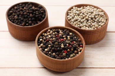 Photo of Aromatic spices. Different peppers in bowls on wooden table