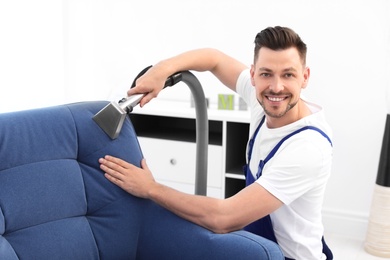 Dry cleaning worker removing dirt from armchair indoors