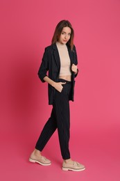 Photo of Full length portrait of beautiful young woman in fashionable suit on pink background. Business attire