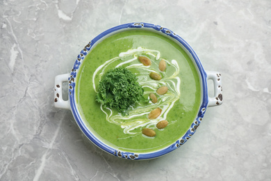 Photo of Tasty kale soup with pumpkin seeds on light grey marble table, top view