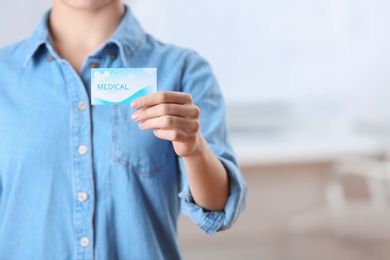 Photo of Woman holding business card indoors, closeup with space for text. Medical service