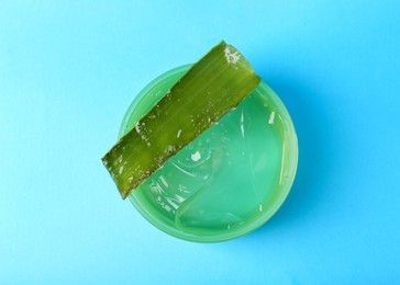 Aloe gel and plant on light blue background, top view