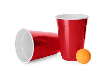 Red plastic cups and ball for beer pong on white background