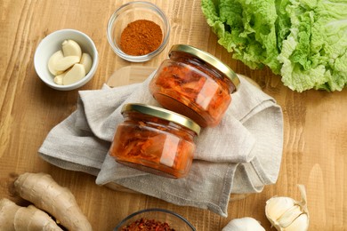 Photo of Delicious kimchi with Chinese cabbage and ingredients on wooden table, above view