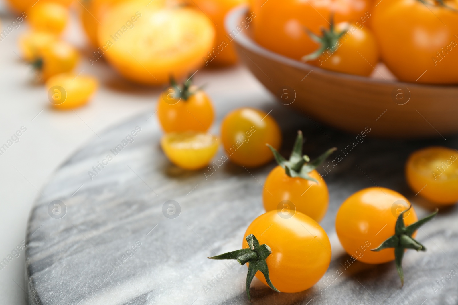 Photo of Ripe yellow tomatoes on marble board, closeup. Space for text