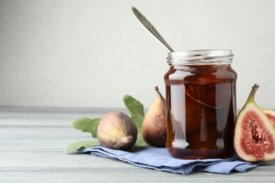 Jar of tasty sweet jam and fresh figs on grey table, space for text
