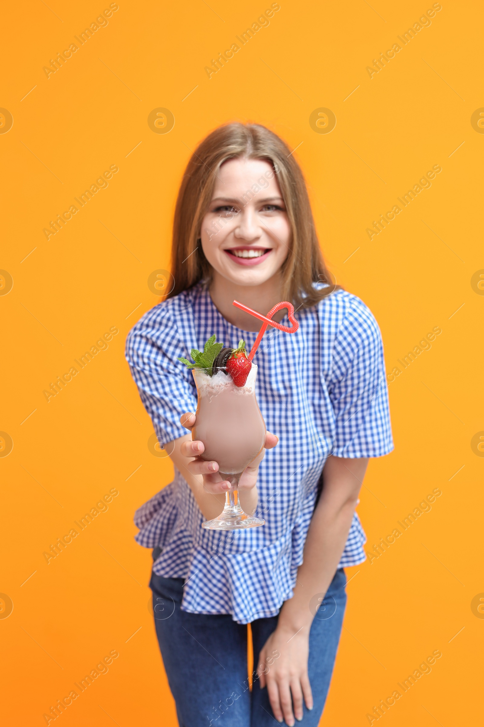 Photo of Young woman with glass of delicious milk shake on color background