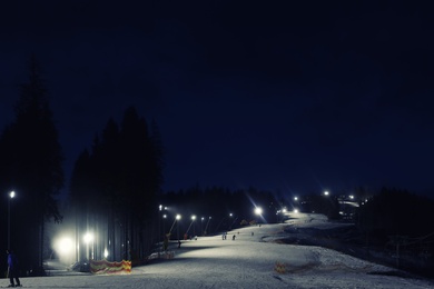 People skiing on snowy piste at night. Winter vacation
