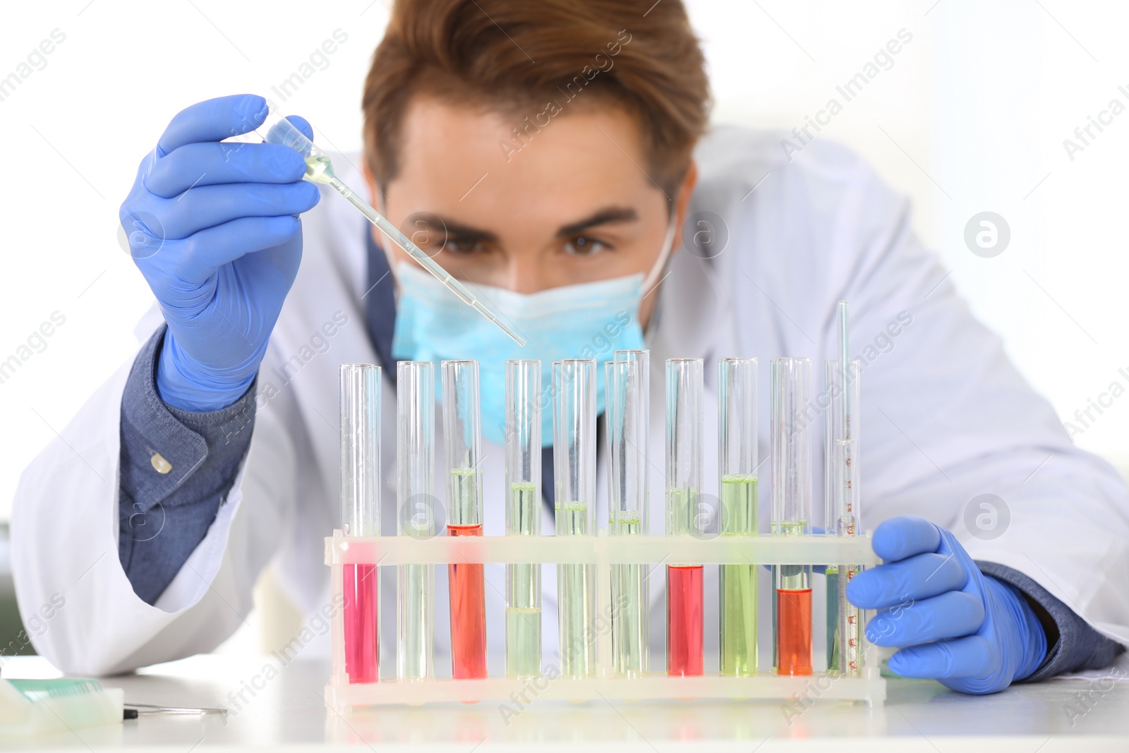 Photo of Male scientist working in laboratory, focus on rack with test tubes. Research and analysis