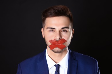 Image of Man with taped mouth on black background. Speech censorship
