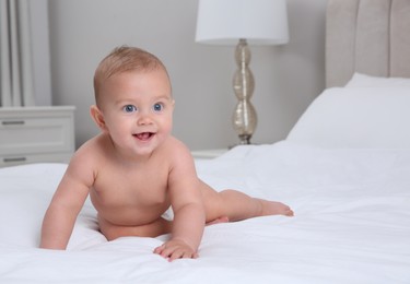 Cute baby in dry soft diaper on white bed at home