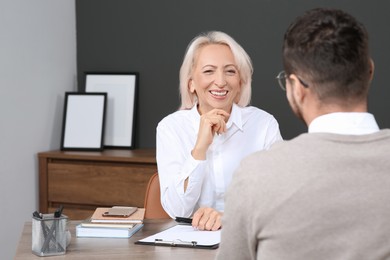 Photo of Happy woman having conversation with man at wooden table in office. Manager conducting job interview with applicant