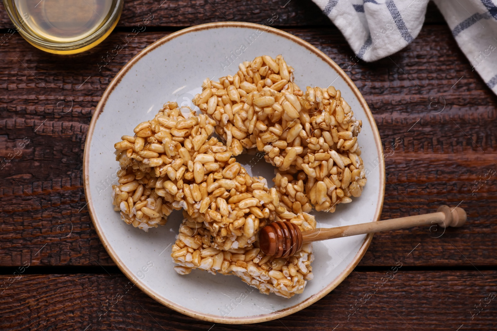 Photo of Plate with puffed rice bars (kozinaki) on wooden table, flat lay