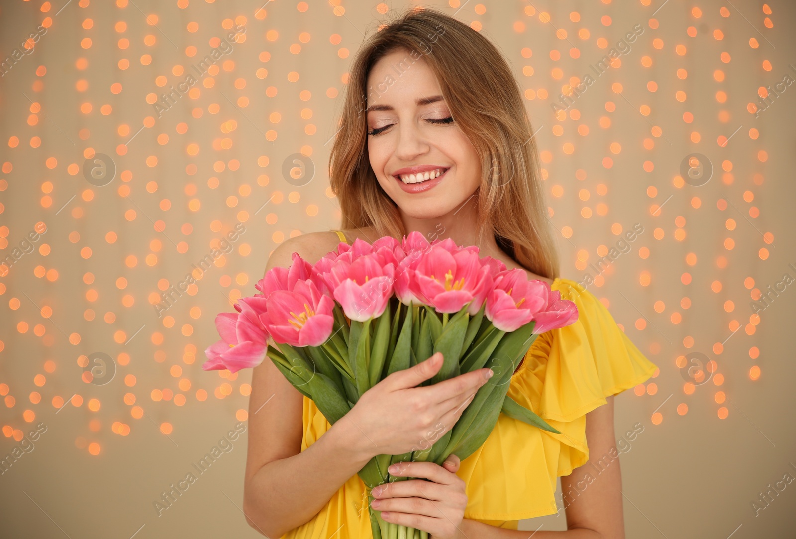 Photo of Portrait of smiling young girl with beautiful tulips on blurred background. International Women's Day