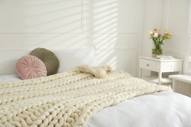 Knitted merino wool plaid on bed indoors. Interior design