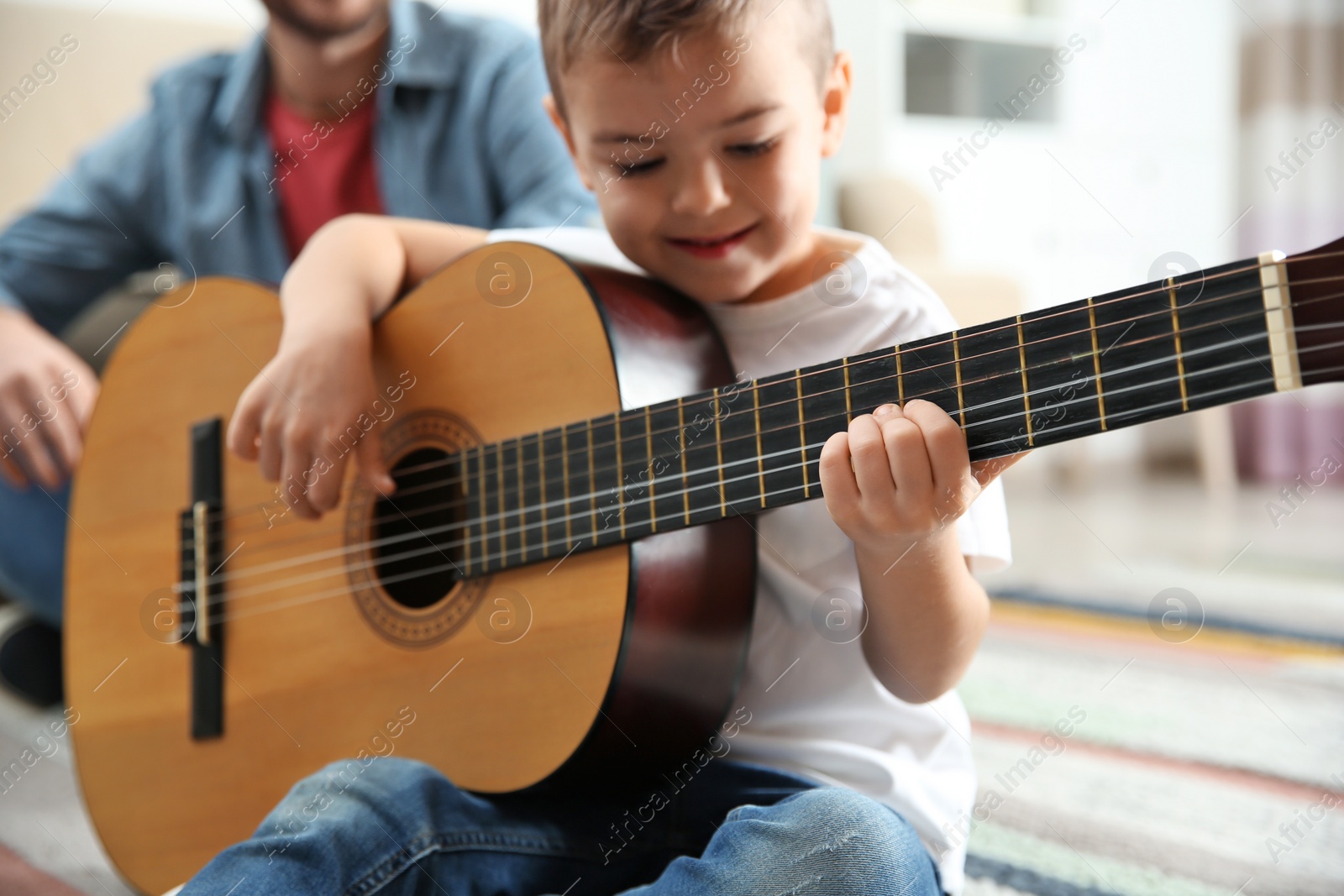 Photo of Father watching his son playing guitar at home