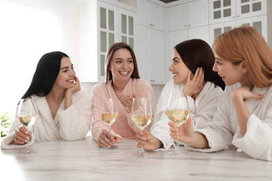 Photo of Beautiful young ladies with glasses of wine in kitchen. Women's Day