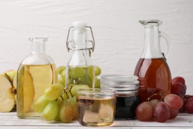 Photo of Different types of vinegar and ingredients on wooden table, closeup