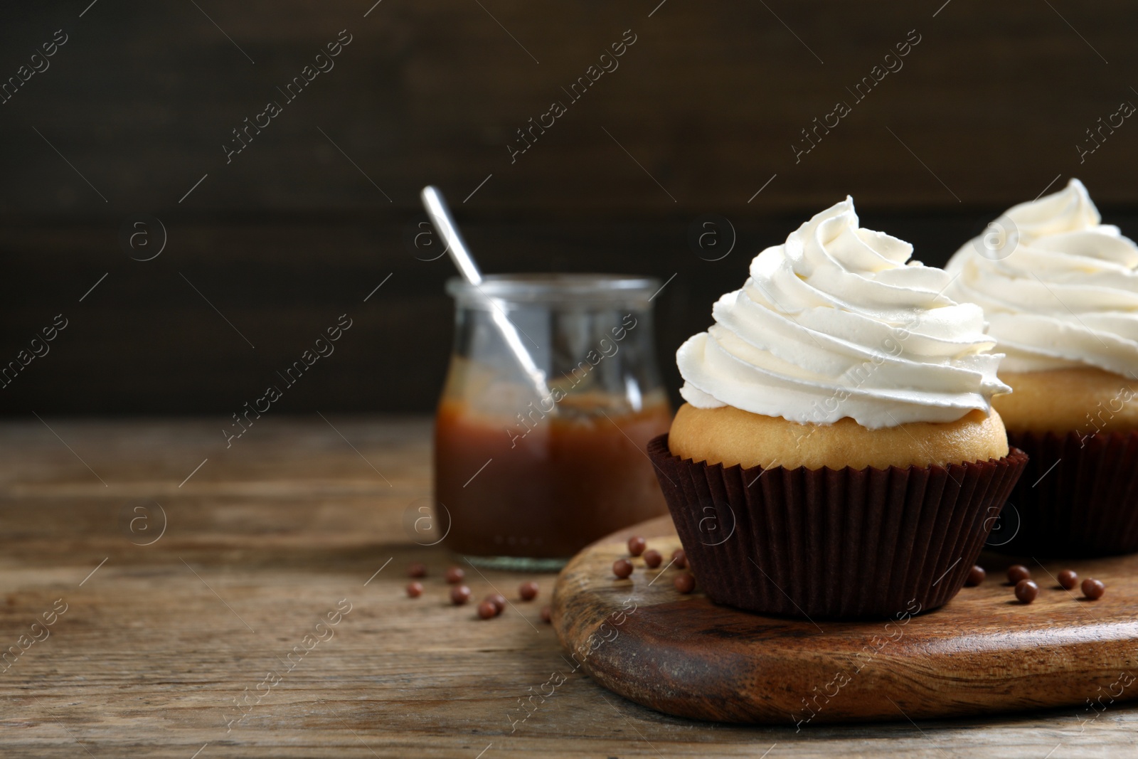 Photo of Delicious cupcakes with cream on wooden table. Space for text