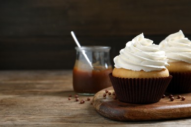 Photo of Delicious cupcakes with cream on wooden table. Space for text