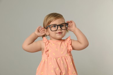 Photo of Cute little girl in glasses on light grey background
