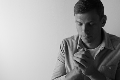 Photo of Man praying on light background with space for text. Black and white effect