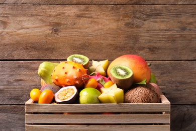 Crate with different exotic fruits on wooden background
