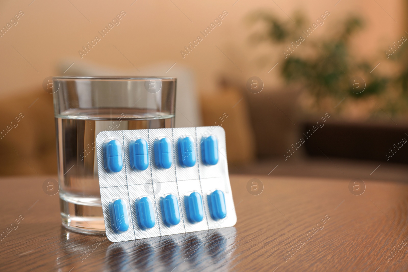 Photo of Glass of water and pills on wooden table indoors, space for text. Potency problem concept