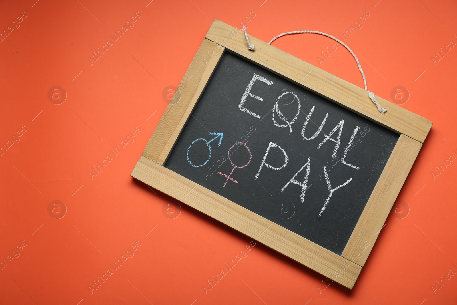 Photo of Blackboard with words Equal Pay and gender symbols on orange background, top view. Space for text