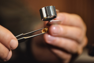 Photo of Jeweler working with gemstone on blurred background, closeup