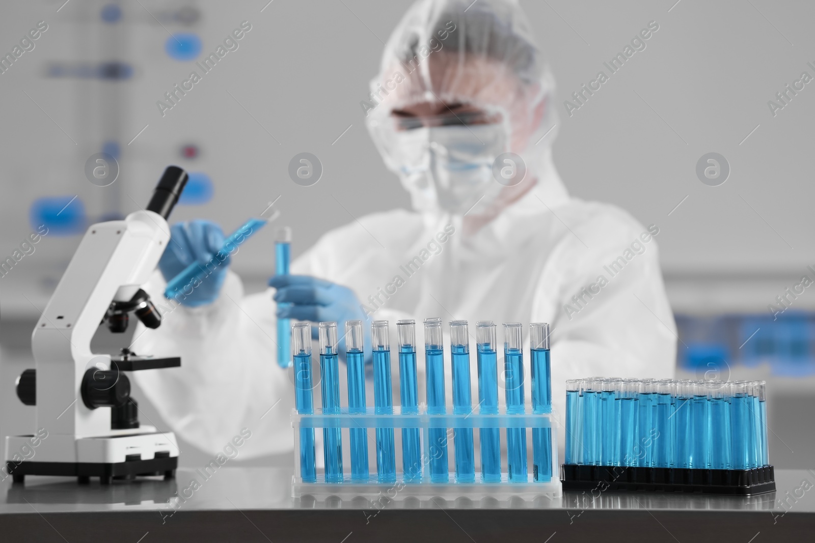 Photo of Scientist holding test tubes with light blue liquid and telescope in laboratory